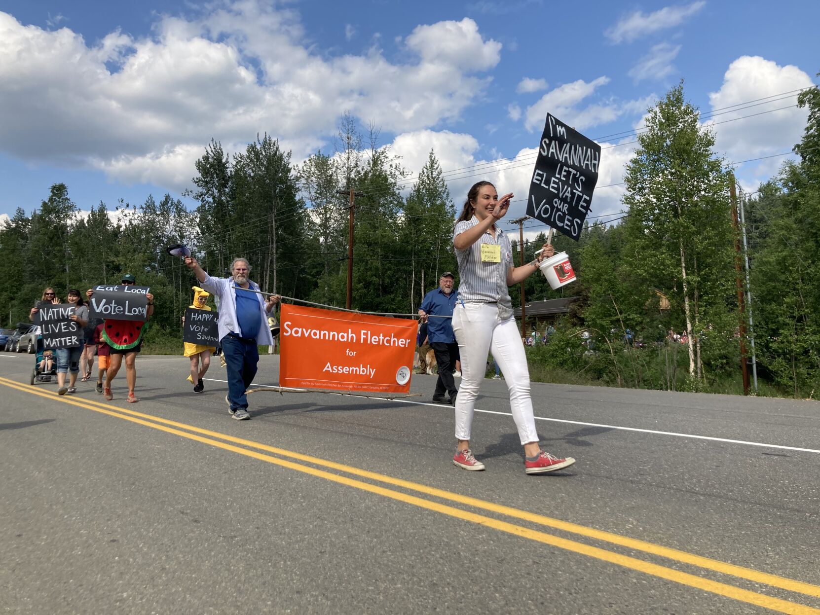 Savannah Fletcher campaigns for a seat on the Fairbanks North Star Borough assembly with fellow candidate David Guttenberg hold her sign behind her.jpeg